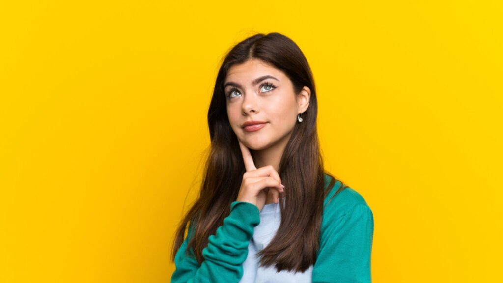Teenager girl over yellow wall thinking an idea
