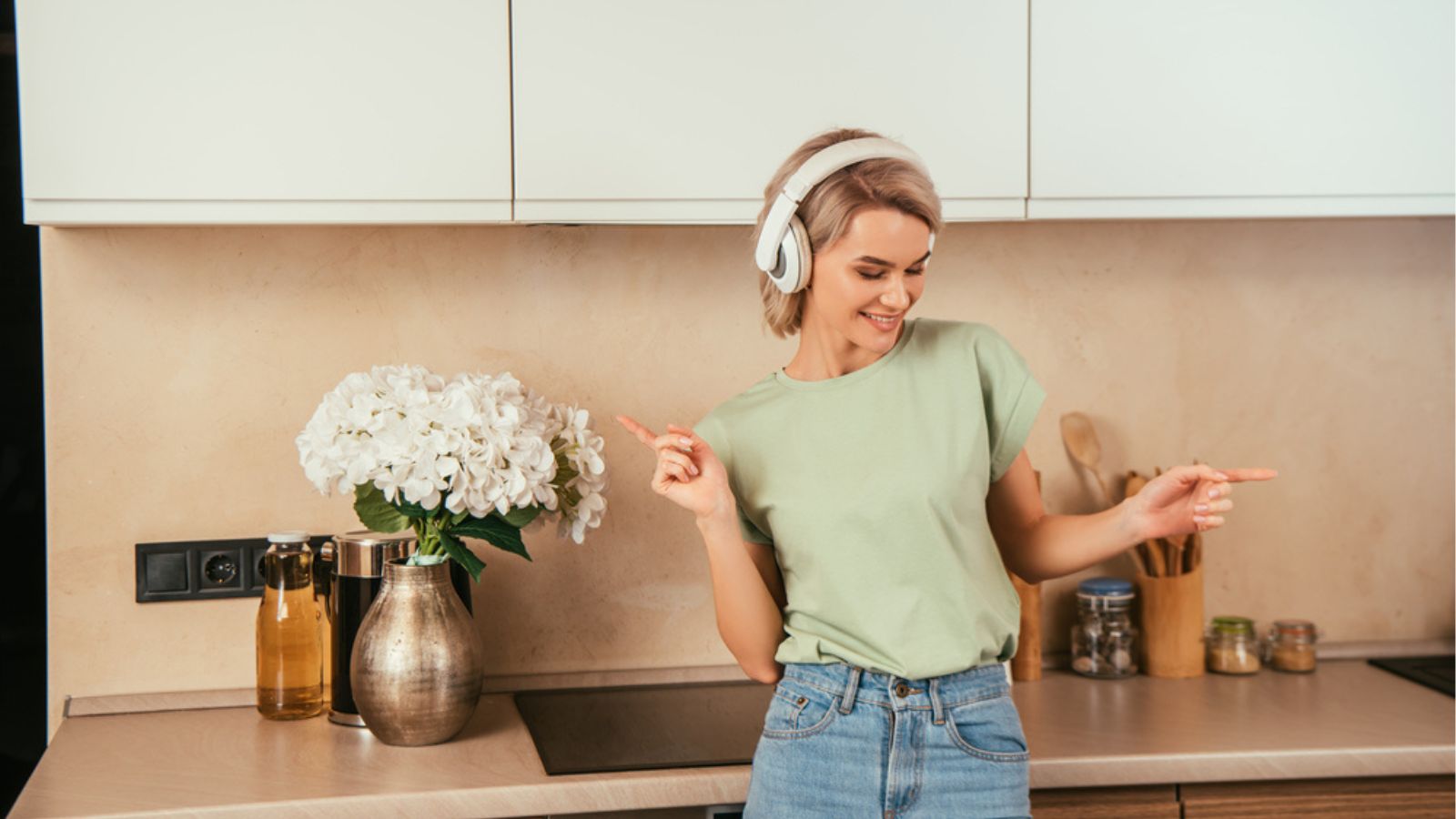 Happy young woman gesturing while listening music in wireless headphone