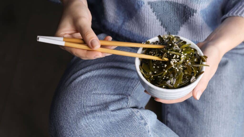 Woman eating fresh laminaria (kelp) seaweed, closeup