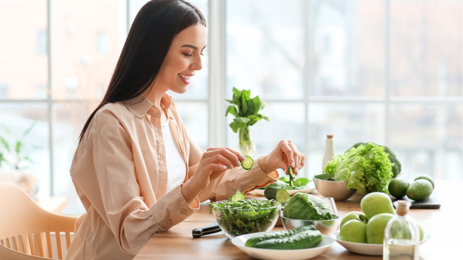 Young woman with fresh leafy green vegetables in kitchen